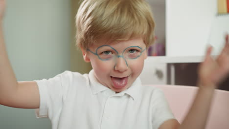 niño en edad preescolar con la cara pintada muestra la lengua y aplaude