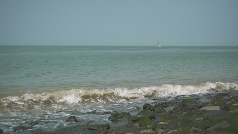 waves on the coast with a sailing ship in the background, slow motion