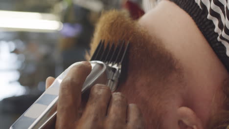 hombre recibiendo cortador de barba con cortadoras de cabello en barbería
