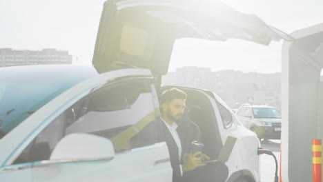 un hombre de negocios cargando un coche eléctrico.