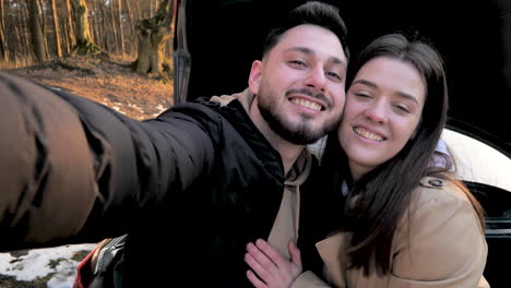 caucasian couple cuddling in a snowed forest.