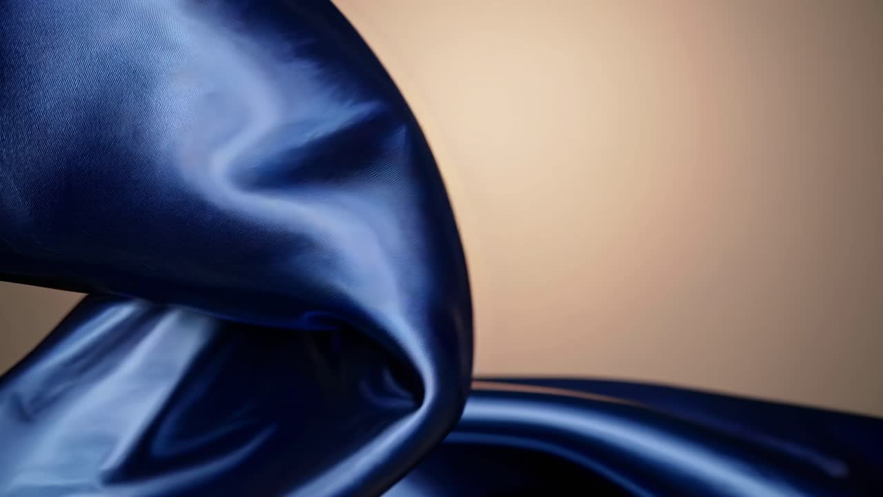 Video astratto di un tessuto blu liscio e fluido, ripreso con un'angolazione ravvicinata, che ne mostra la setosità.