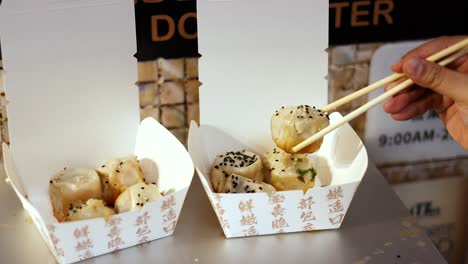 chopsticks picking dumplings from a takeout box