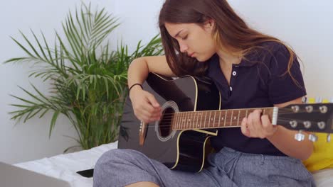 young woman with laptop playing guitar