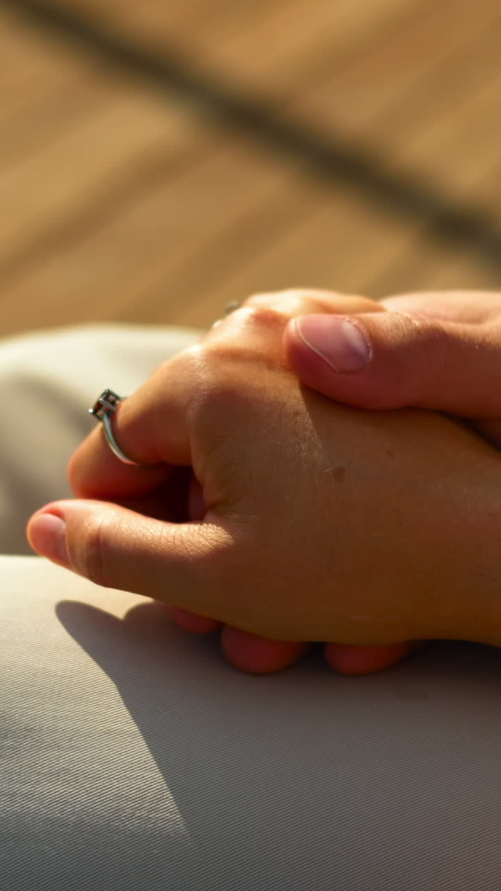 Primo piano di una coppia che si tiene per mano dolcemente alla calda luce del sole