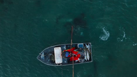 birdseye view of fishermen rowing back to shore with boat full of fish in bahia asuncion mexico