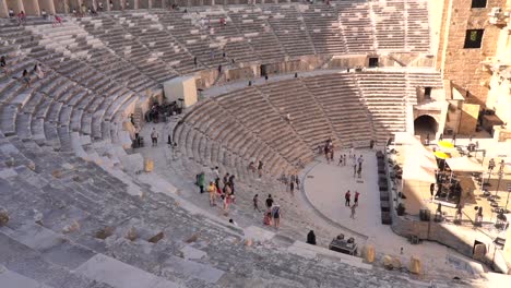a distant view of the ancient theater in the afternoon, with tourists walking back and forth