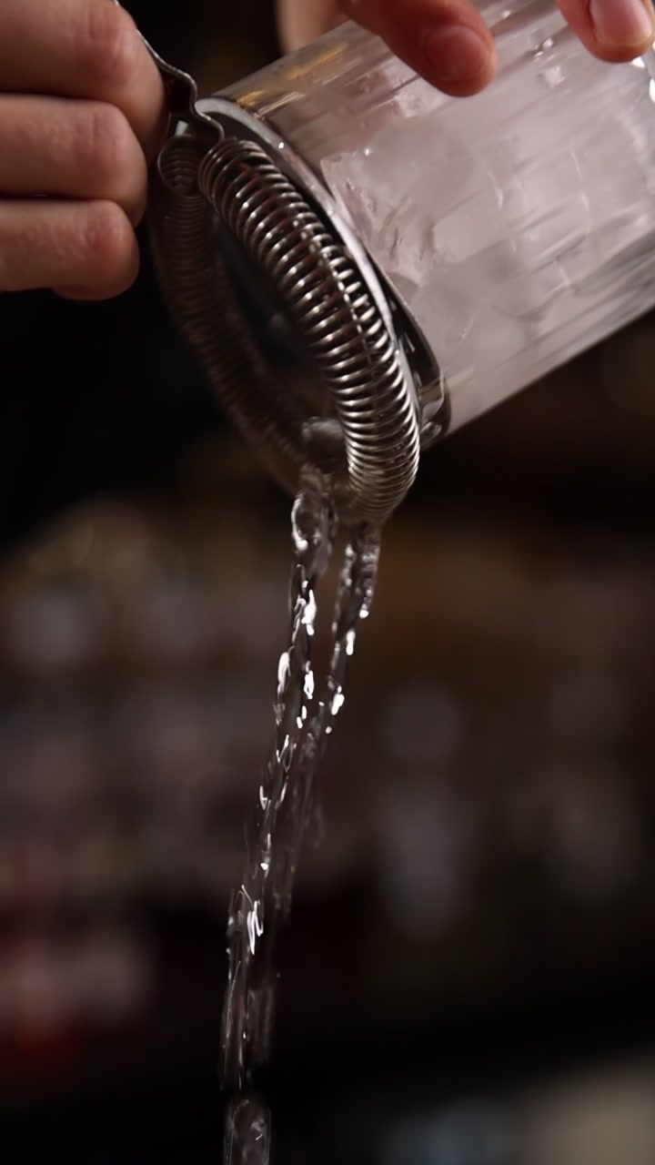 Primo piano di un barman che scola l'acqua da un bicchiere di ghiaccio
