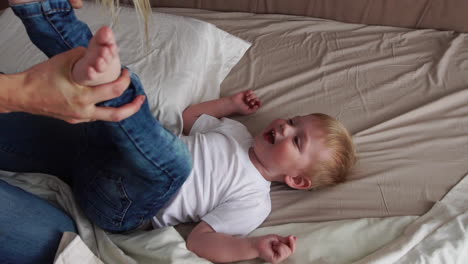 mom and father tickling her child. people, family, fun and morning concept - happy child with parents tickling in bed at home. happy family spending time together in bedtime playing and hugging