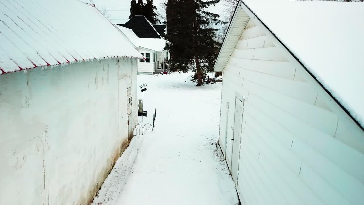 Slow aerial shot between two barns to reveal 19th century farmhouse in the winter. 4K