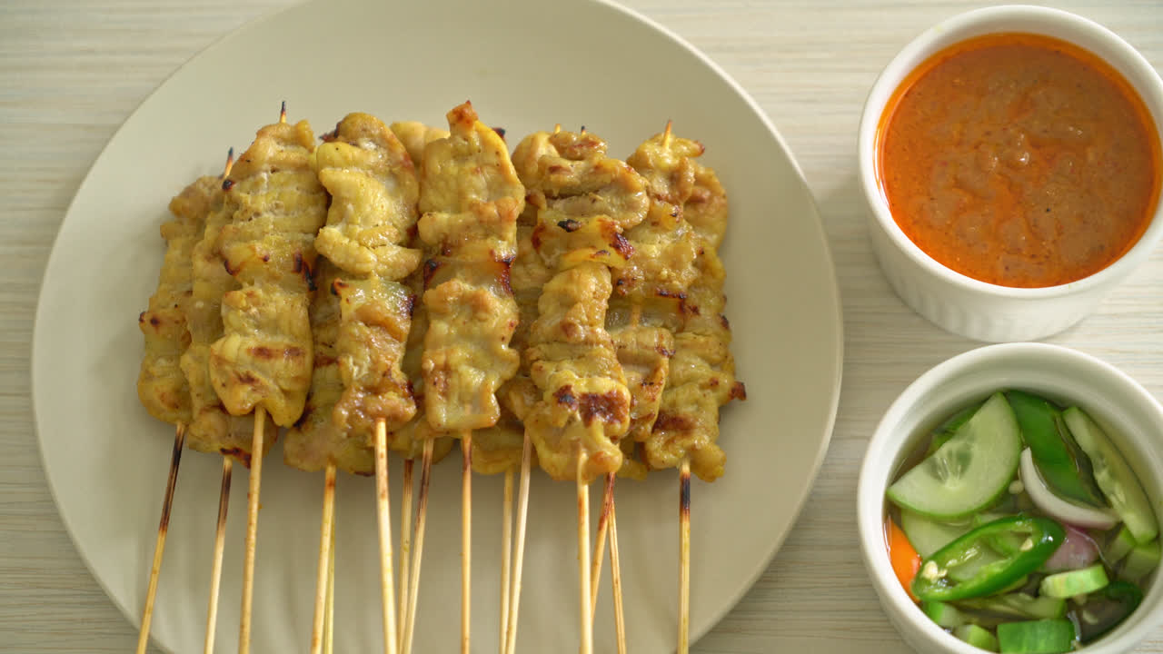 Possuvarras satay-kastikkeella sekä suolakurkuilla, jotka ovat viipaleiksi leikattuja kurkkuja ja sipuleita viinietikassa – aasialainen ruokatyyli