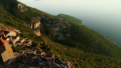 Drone-descends-swooping-along-cliffside-overlooking-Lubenice-Croatia