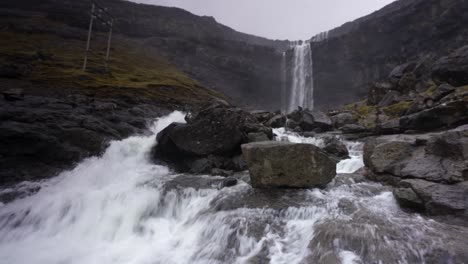 alejar la toma de la enorme cascada fossarfoss que se estrella en la isla streymoy durante el día nublado - la cascada más alta en las islas feroe