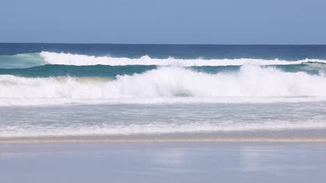 continuous ocean waves rolling onto a sandy beach