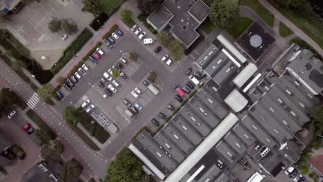 Movimiento-Aéreo-Ascendente-Que-Revela-Un-Estacionamiento-De-Coches-En-Un-Centro-Comercial-En-Un-Barrio-Residencial-Holandés