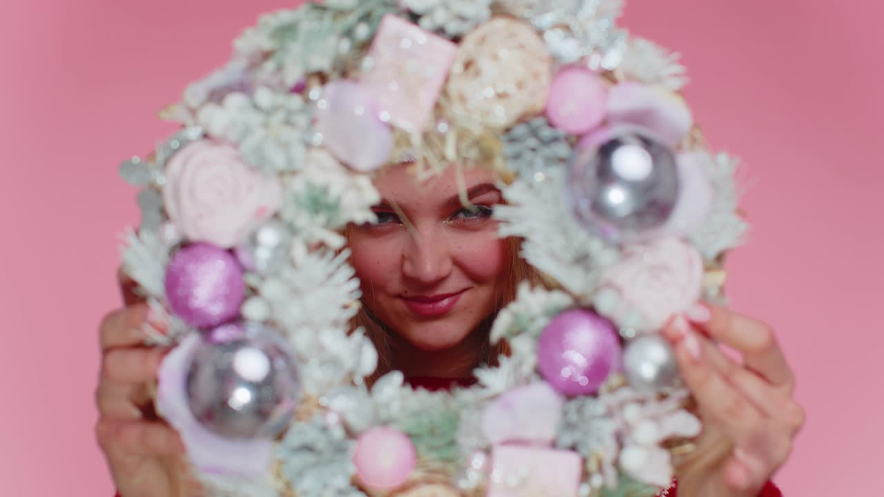 행복한 여성은 빨간 새해 크리스마스 스웨터와 모자를 입고 축제 꽃받침을 올리고, 뒤에 숨어 있습니다.