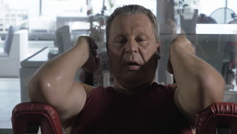 hombre cansado y sudoroso entrenando en una máquina de fitness