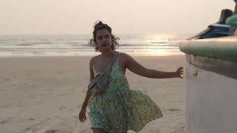 girl walking on the beach with an money belt and a summer dress at sunset next to a fishing boat, ocean in background