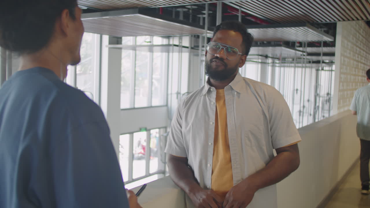 Man Having Conversation with Colleague in Office Corridor