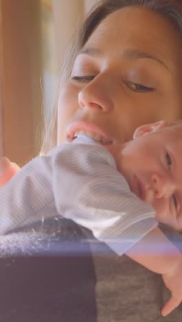 animation of glowing spots over happy caucasian mother with sleeping baby