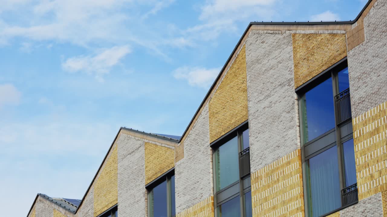 Modern brick building with reflective windows under moving clouds timelapse