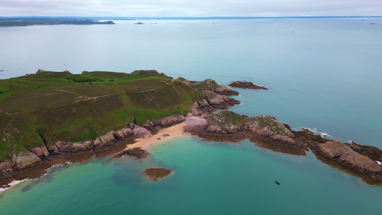 Aerial sideways drone view of the stunning Cap d'Erquy peninsula, showing sandy coves, rocky shores, and turquoise water in Brittany, France