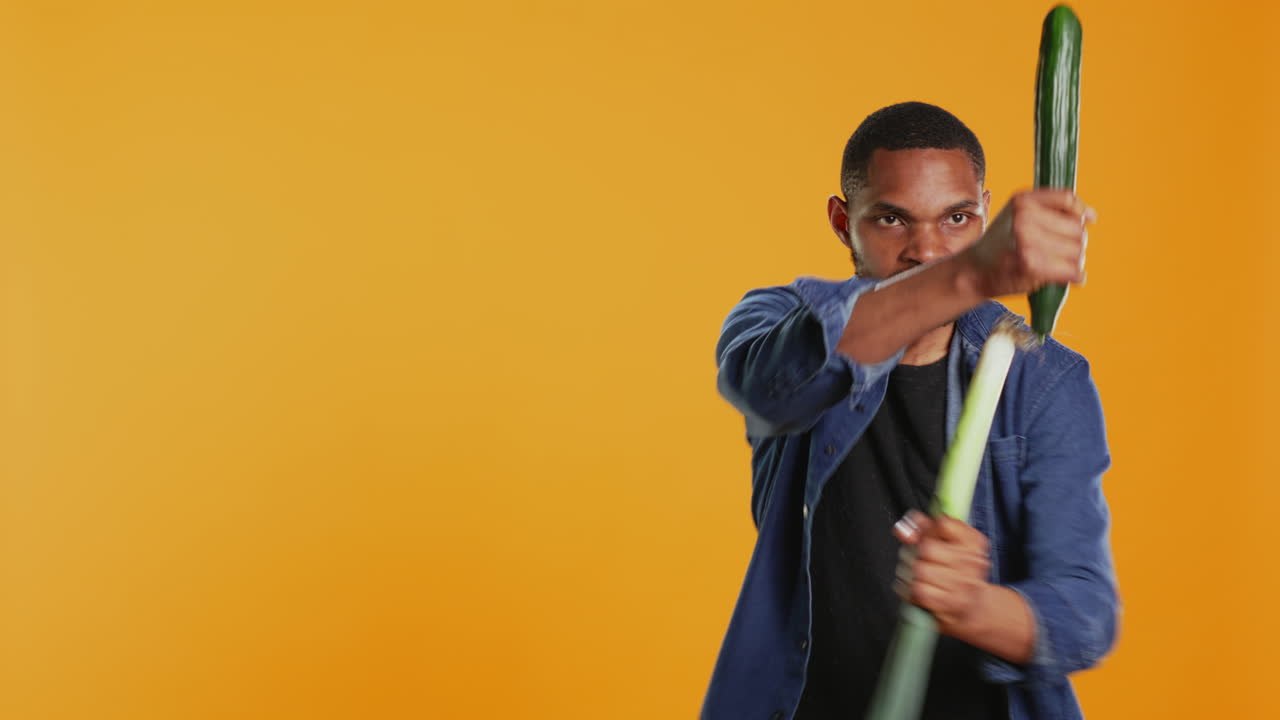 un adulto joven satisfecho fingiendo comenzar una pelea con un pepino y un puré