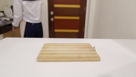 female cook prepares chopping board and bowls of ingredients on the kitchen counter