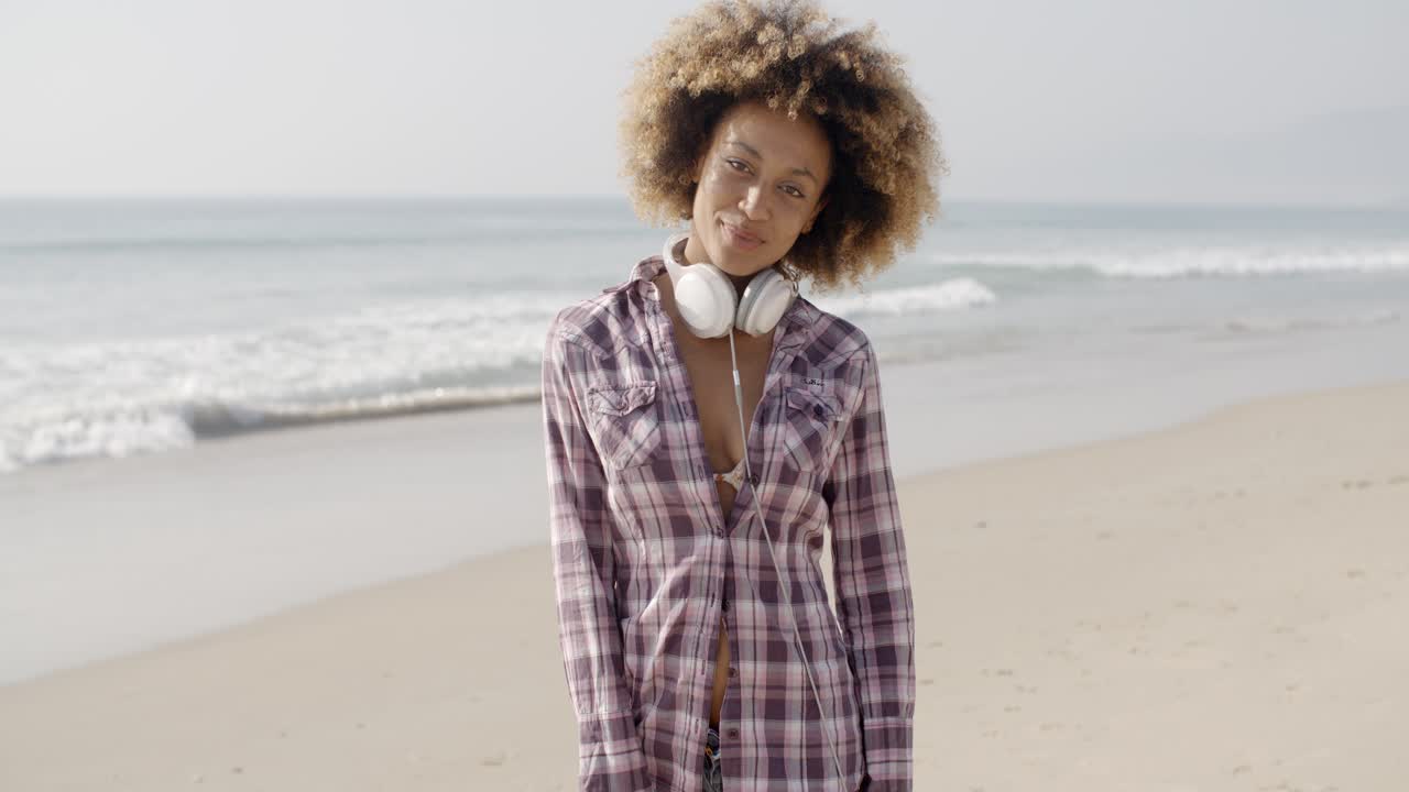 chica con auriculares caminando por la playa