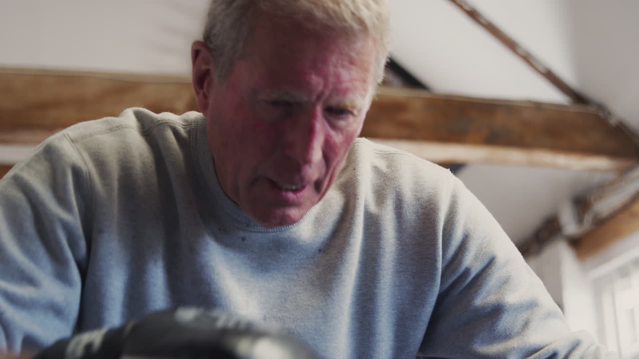 старший мужской боксер в боксерских перчатках тренируется в спортзале, отдыхает на веревках на боксерском ринге