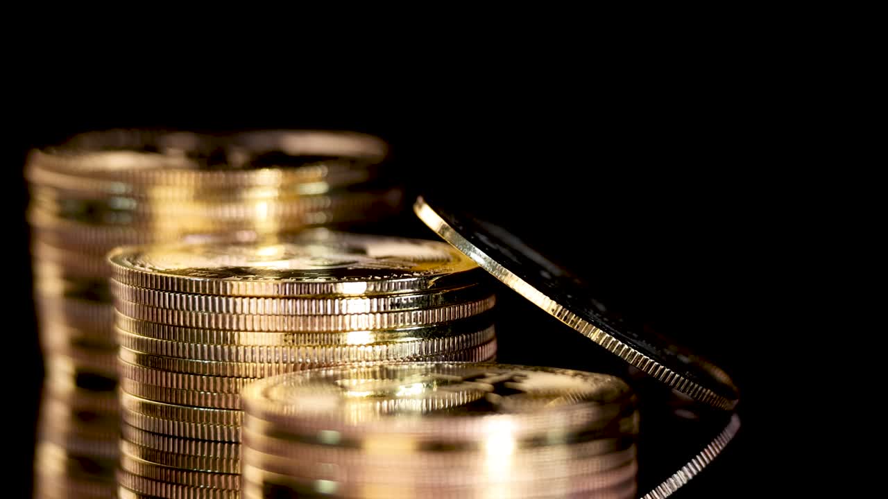 Gold cryptocurrency coin rotates and zooms in against black background, highlighting shiny stacked coins