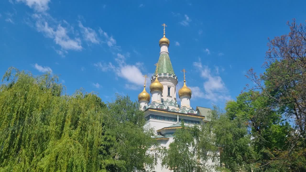 Golden domes and shining crosses of St. Nicholas the Miracle-Maker Church in Sofia, Bulgaria stand out against a vibrant blue spring sky, radiating serenity and light