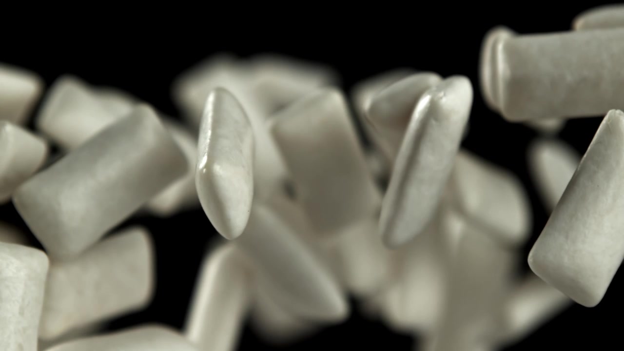 Pezzi di gomma da masticare bianca che galleggiano su sfondo nero.