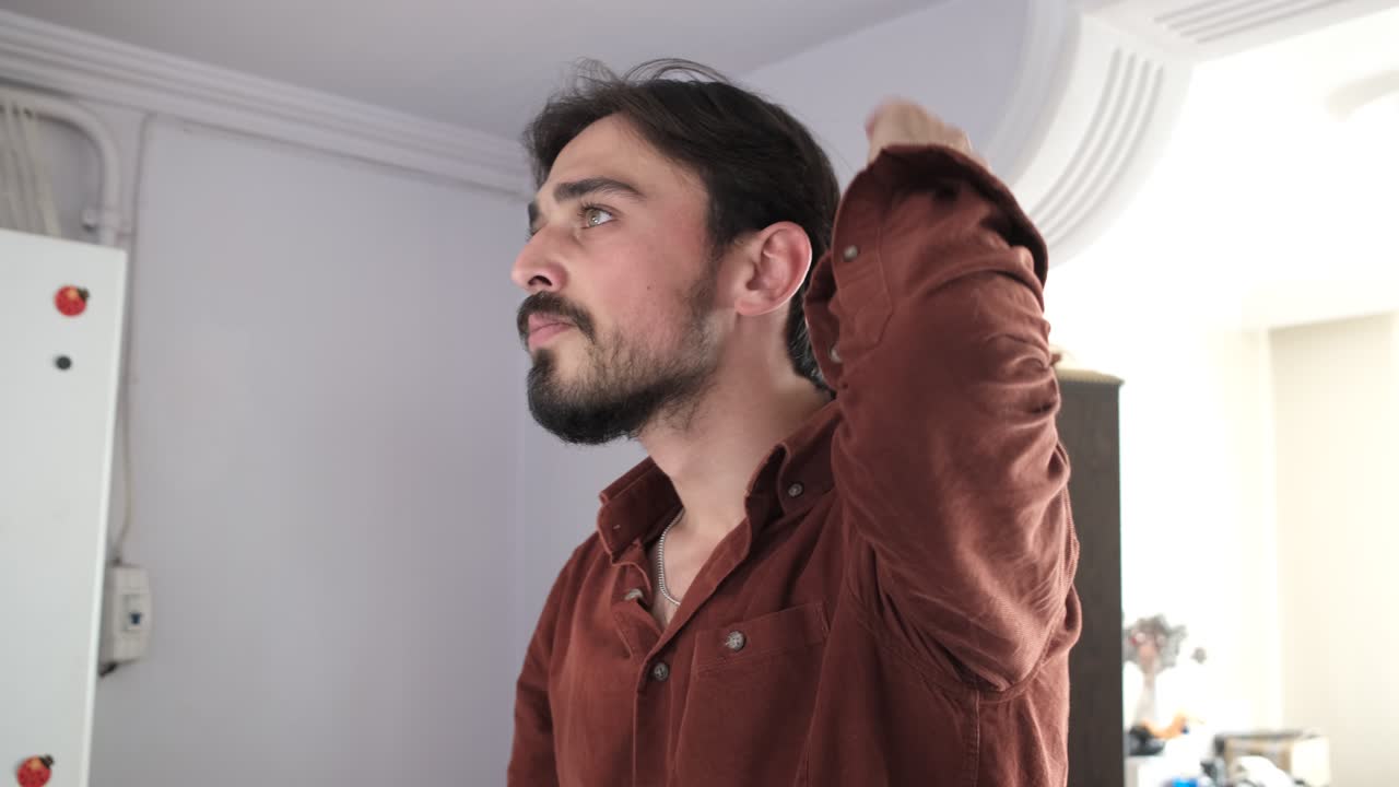 Handsome young man combing his hair while standing in front of the mirror, a guy brushing his hair, people look at themselves in the mirror