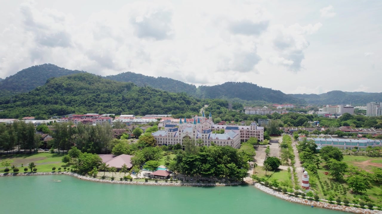 Langkawi kıyı şeridi boyunca tropikal dağların fonunda yer alan, zarif, kale esintili bir sahil tesisini ve manzaralı bir sahil şeridini sergileyen güzel havadan çekimler