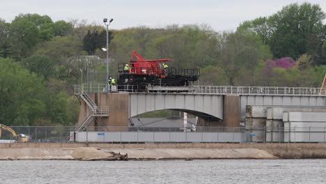 small crew of men walking along side a specialized crane moving on rails at lock and dam number 14 on the mississippi river, near leclair, iowa usa