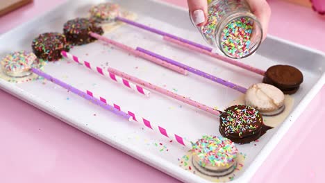 decorating cake pops with melted black and white chocolate with colorful crumbs