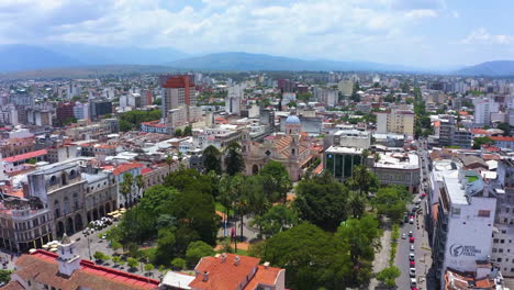 AERIAL---Plaza-9-de-Julio-square,-park-and-church-in-Salta,-Argentina,-rising-reverse