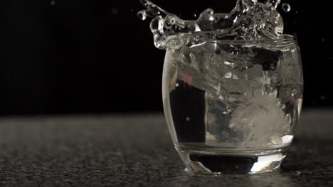 ice cube falling into glass of water