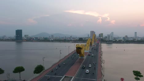 giro aéreo alrededor del puente del dragón cau rong, tráfico y horizonte de la ciudad durante la puesta de sol en danang, vietnam