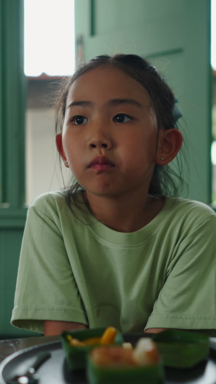 Primo piano di una giovane bambina asiatica seduta e pensierosa