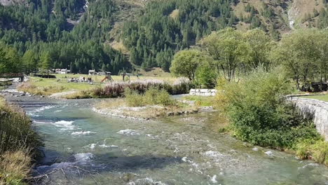 children and families having fun in a park between the mountains and close to a river