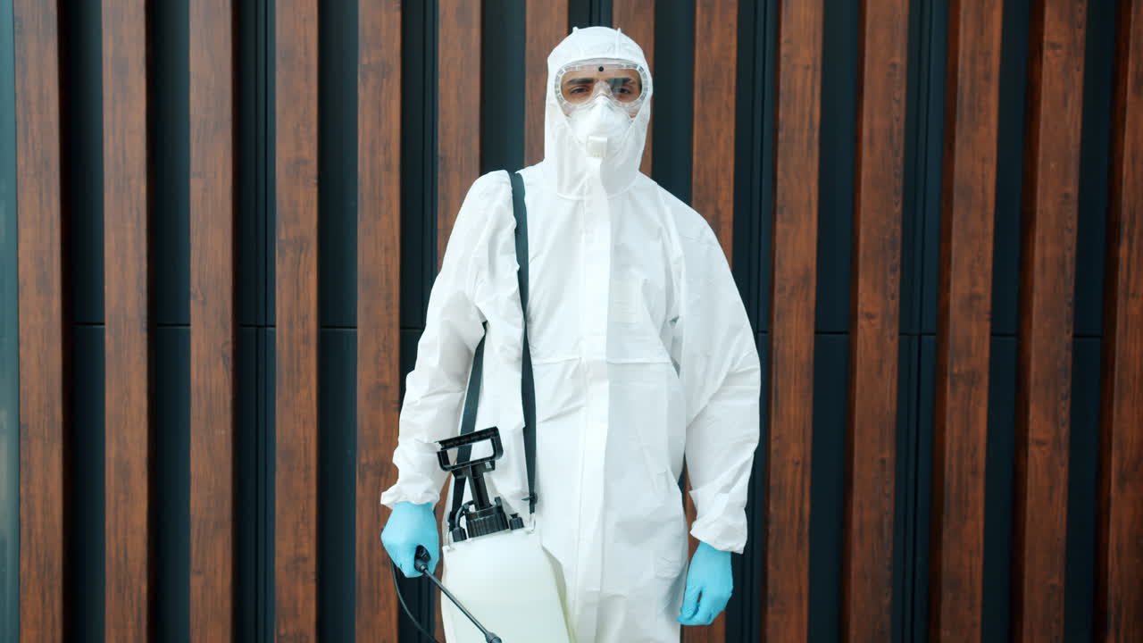 Worker in protective suit spraying disinfectant