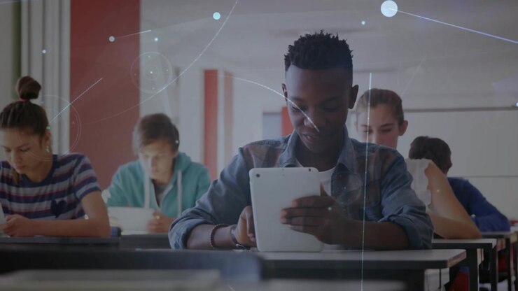 Teenage boy tapping tablet in classroom initiating glowing network overlay showing education tech