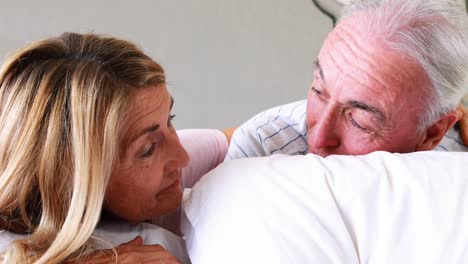 pareja de ancianos felices interactuando entre sí en la cama