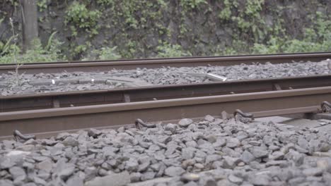 low angle view of train tracks with fast train passing by - static shot