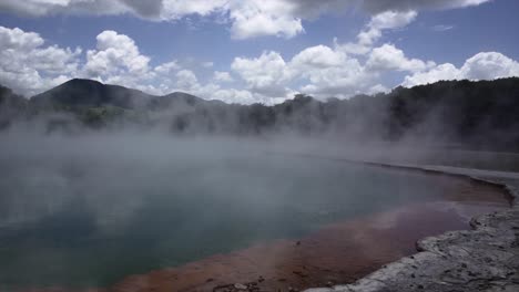 geothermal lake with steam and mountains