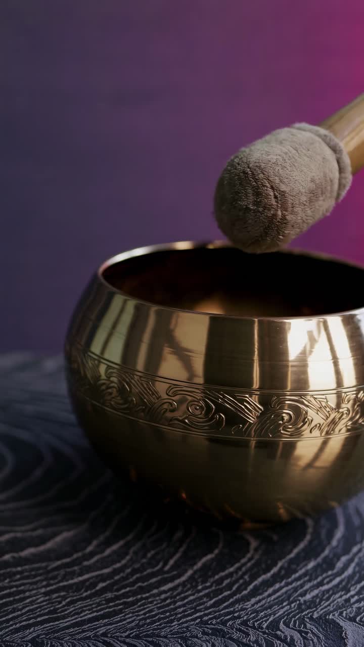 Video in primo piano di una mano che suona una campana tibetana in ottone, che mette in risalto disegni intricati.