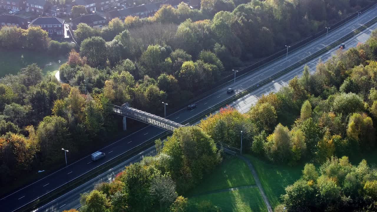 Aerial view rising above countryside dual carriageway traffic country road between woodland treetop at sunrise