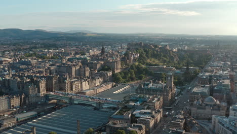 Dolly-back-drone-shot-of-Central-Edinburgh-Princes-street-Calton-hill-at-sunset